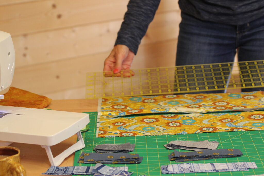 Tracy aligning a long quilting ruler on fabric on cutting mat — how to square up fabric for quilting