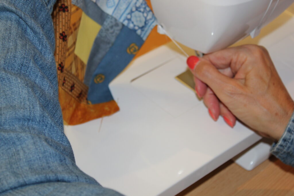 Tracy's hands guiding patchwork through sewing machine at needle — seam allowance in quilting explained