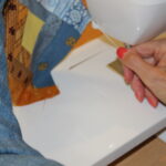 Tracy's hands guiding patchwork through sewing machine at needle — seam allowance in quilting explained