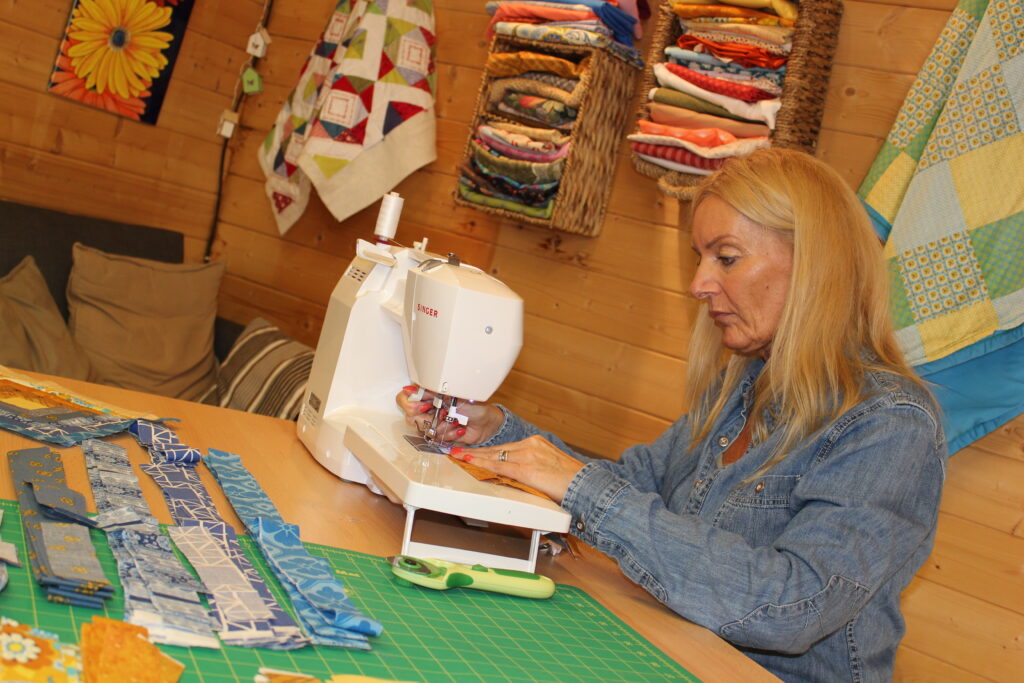 Tracy in her quilting studio with finished quilts on the wall behind her — common quilting mistakes beginners make