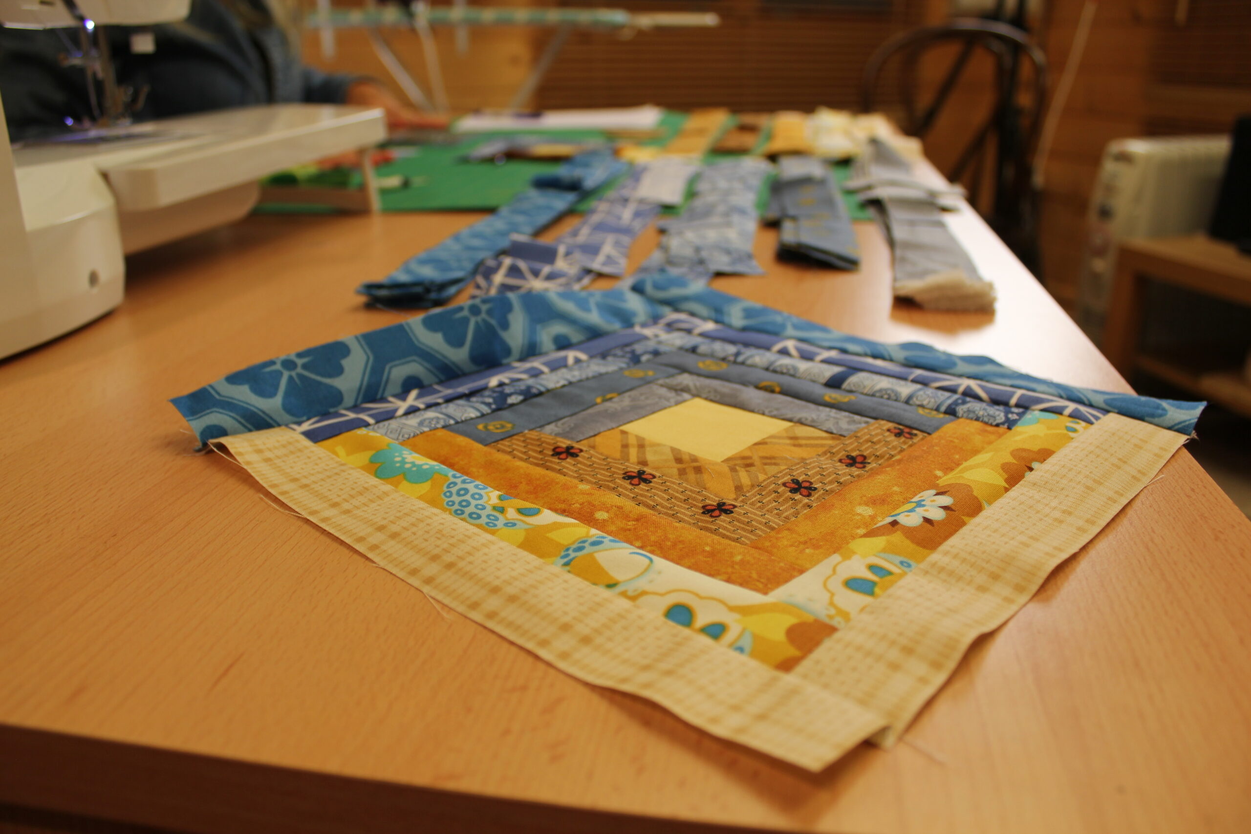 finished patchwork quilt block in warm colours on table — beginner quilting project from start to finish