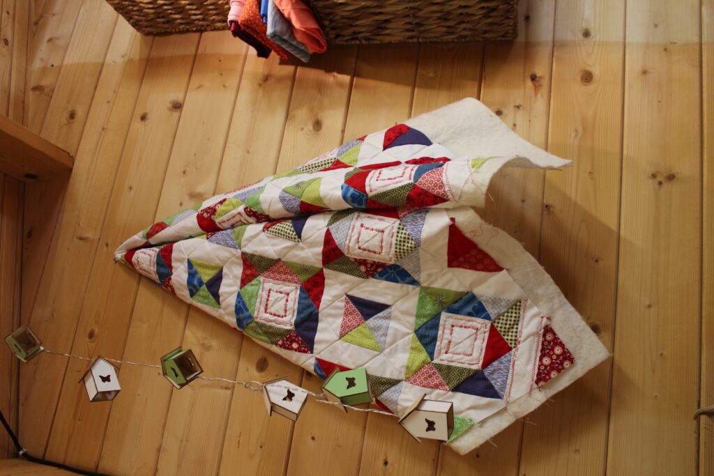 colourful triangle quilt hanging on wooden wall with half square triangle blocks for beginners