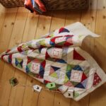 colourful triangle quilt hanging on wooden wall with half square triangle blocks for beginners