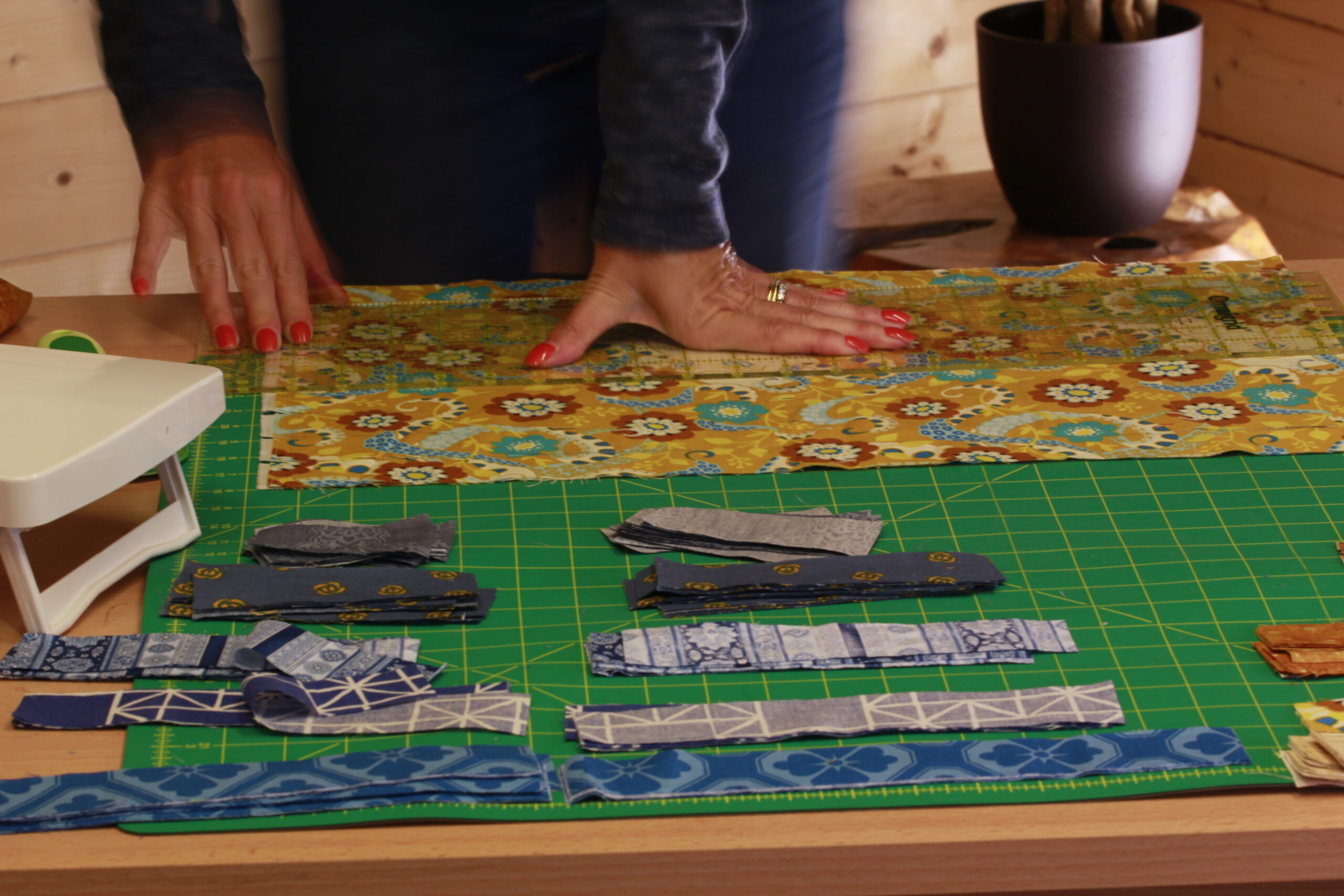 hands pressing fabric flat on quilting cutting mat for beginner quilting