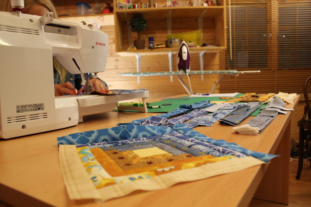 log cabin quilt block on table with sewing machine in studio background