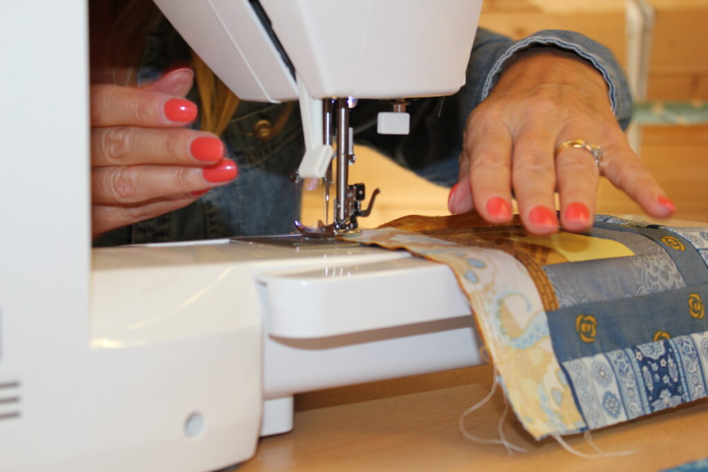 hands feeding patchwork through sewing machine showing seam alignment for quilt points
