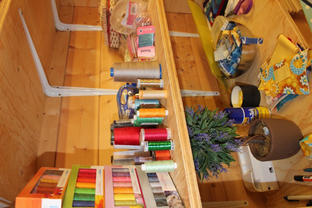 quilting thread spools in rainbow colours on studio shelf for beginners