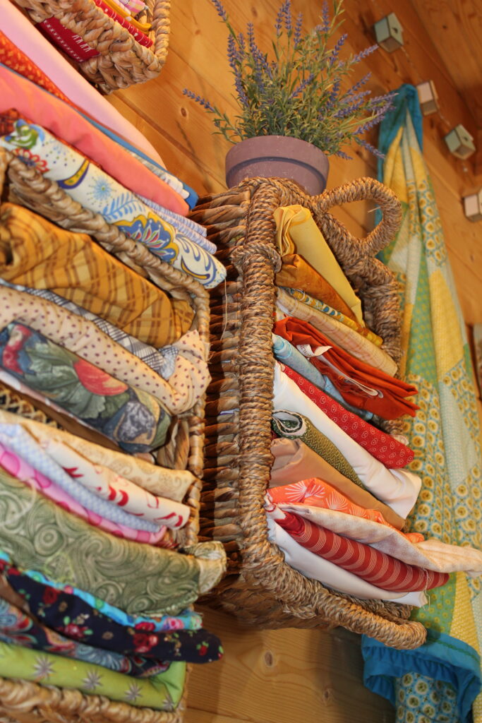 fat quarter bundles in a wicker basket showing coordinating prints for how to choose fabric for quilting beginners