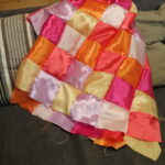 satin patchwork squares arranged on a sofa showing colourful beginner quilt block patterns