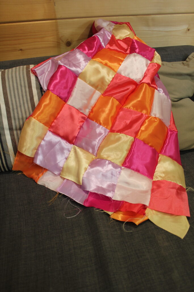 satin patchwork squares arranged on a sofa showing colourful beginner quilt block patterns