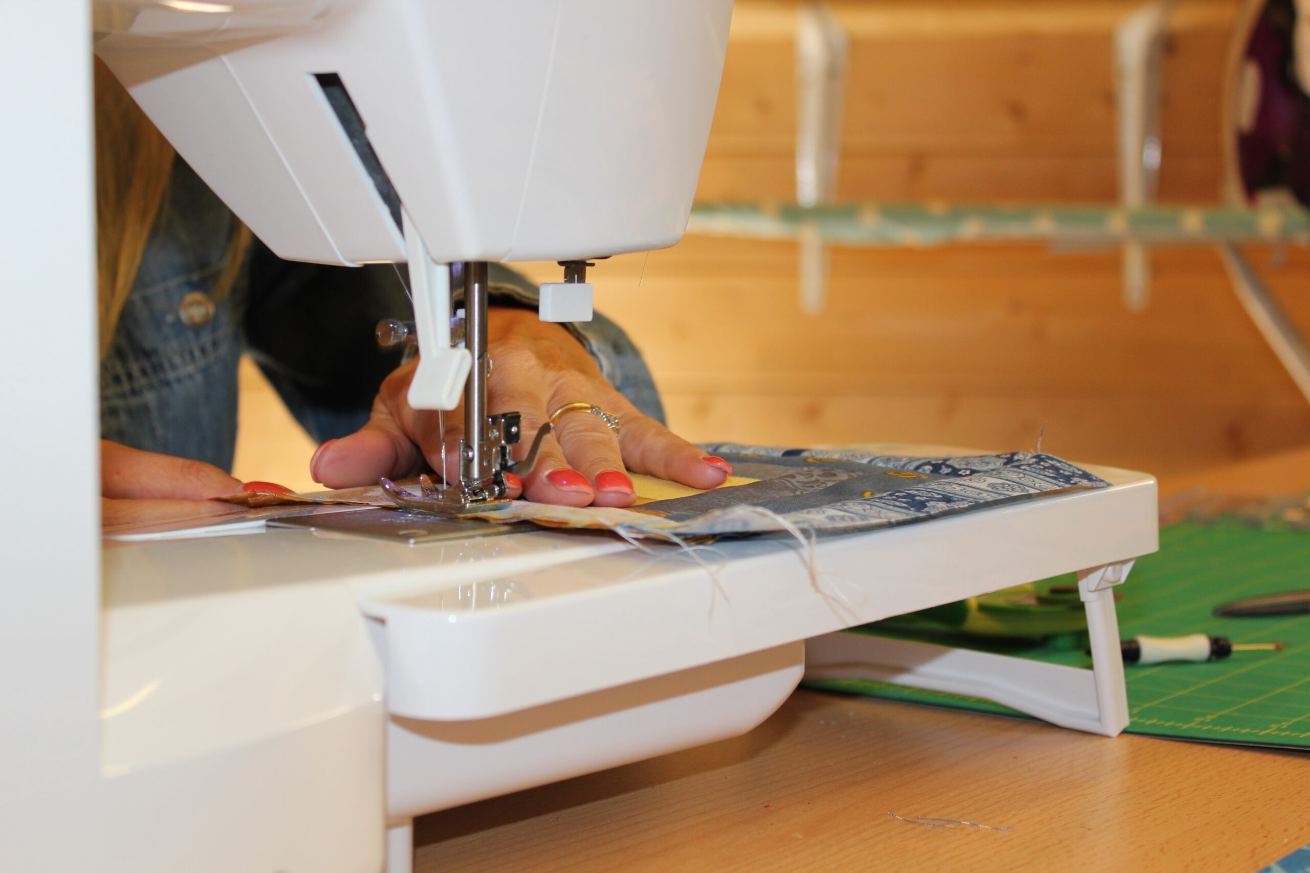 hands guiding patchwork fabric through sewing machine for first quilting project — scared to start quilting